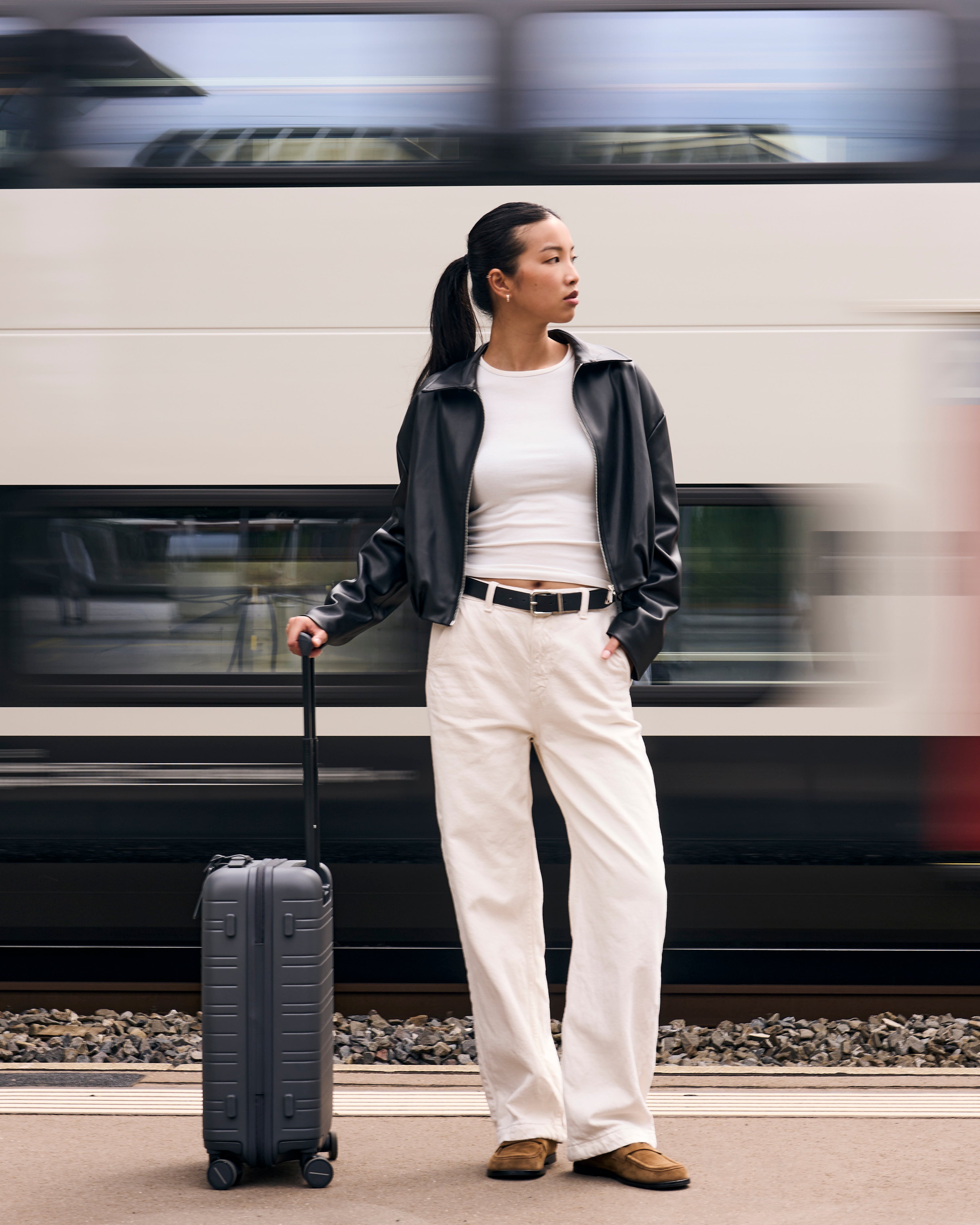 suitcase standing on a platform as a train passes by - Horizn Studios